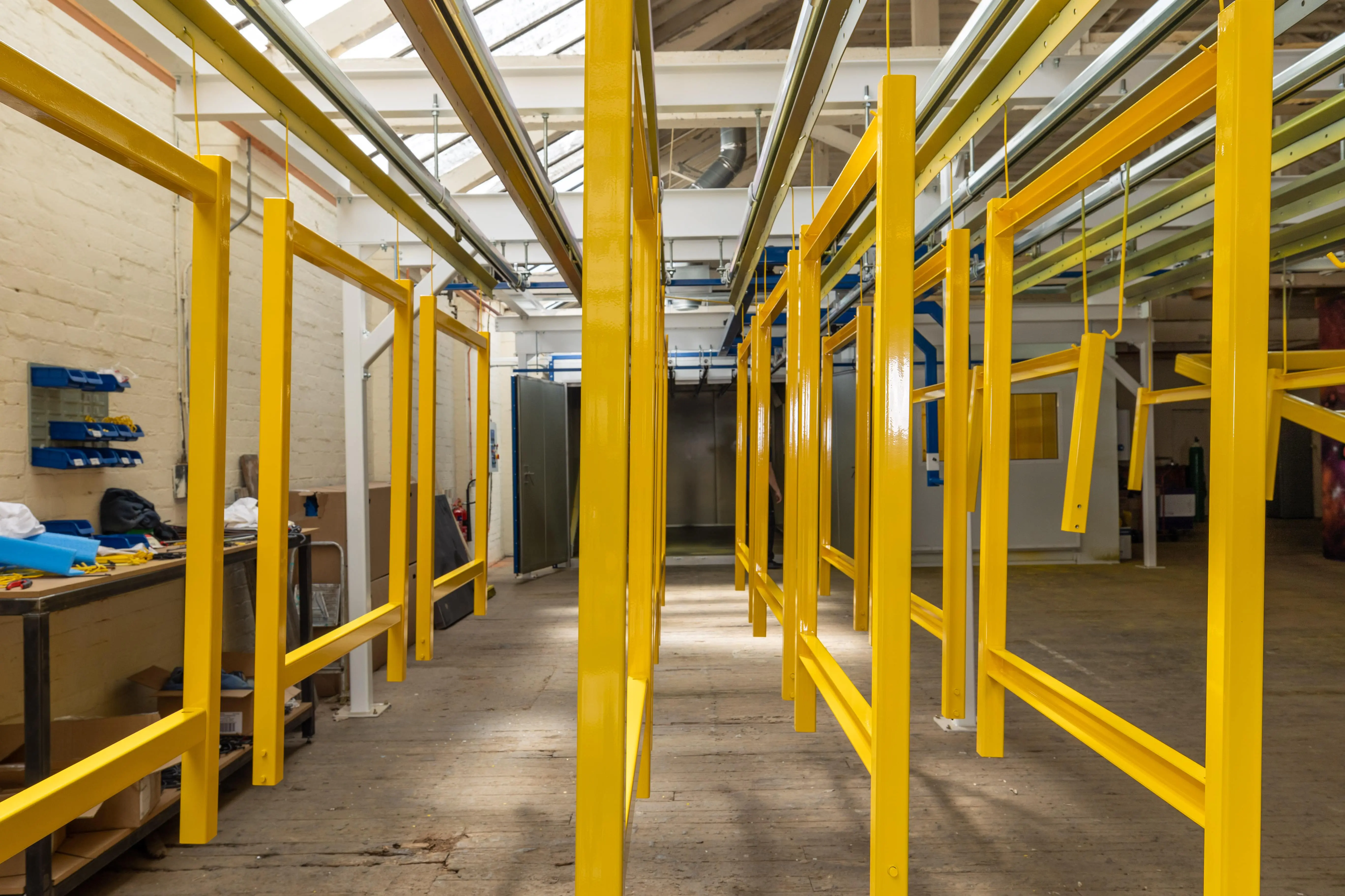 Yellow railings hanging from Fastlok Manufacturing's Powder Coating line.